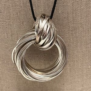 N125 Multiple hammered flat metal strips create a pendant with knot on cord